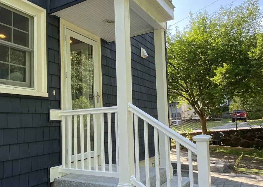 Dark gray home with a new white-railed porch and steps