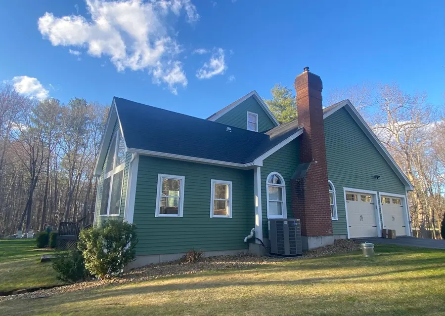 Green two-story home with fresh white trim and a new deck
