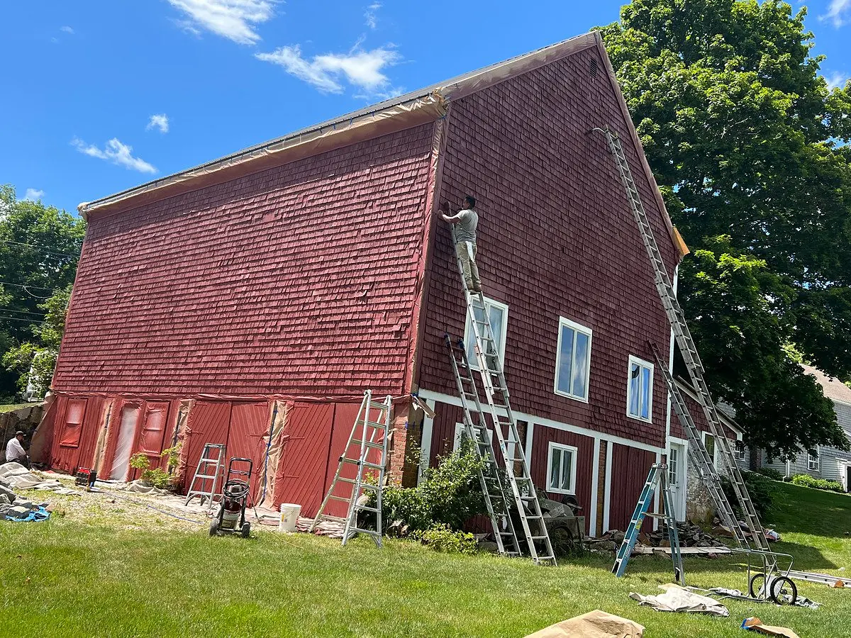 Before: red barn with peeling paint restored