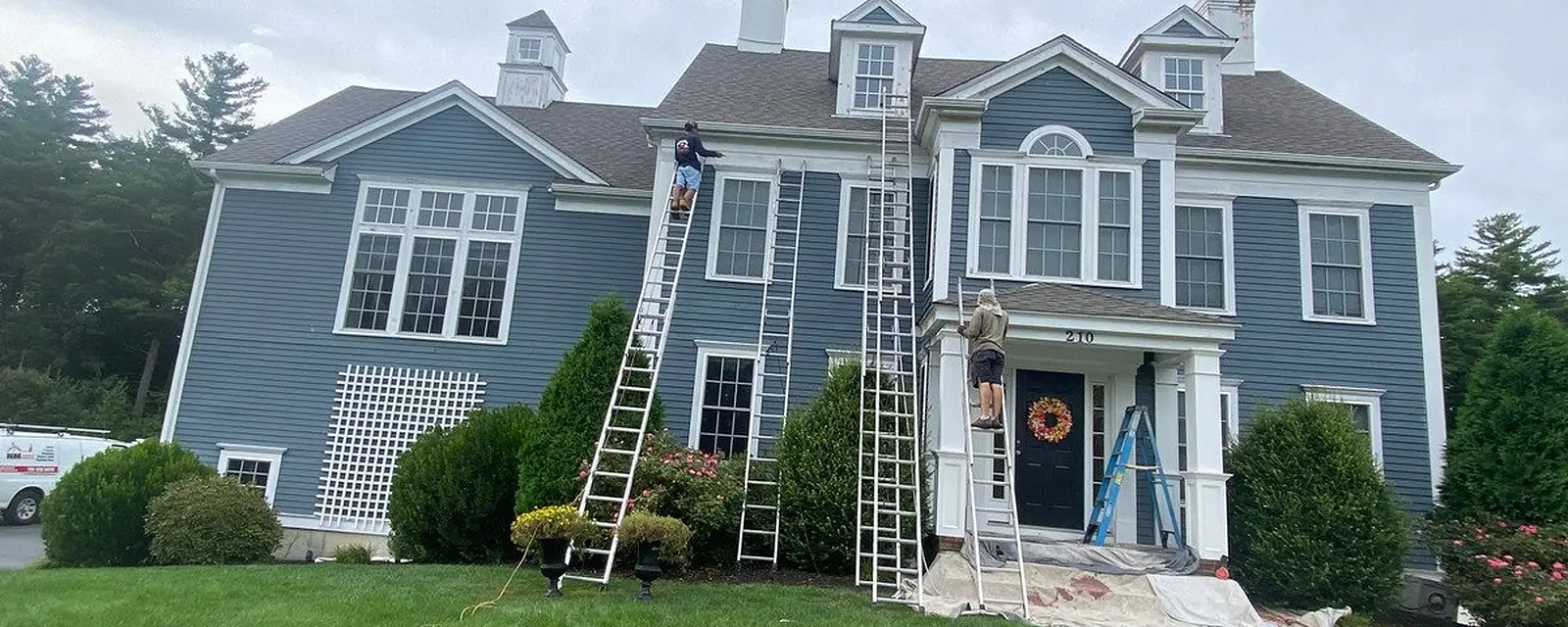 Crew on ladders painting a two-story home