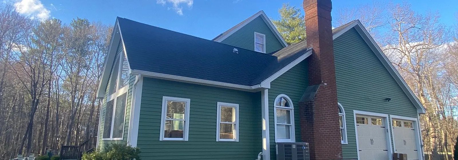 Green two-story home with fresh white trim and a new deck
