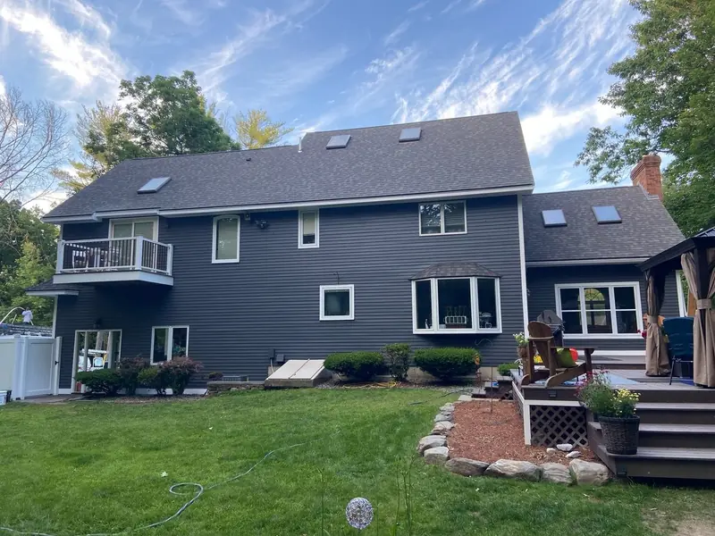 Two-story home painted dark gray with white trim and a rebuilt rear deck