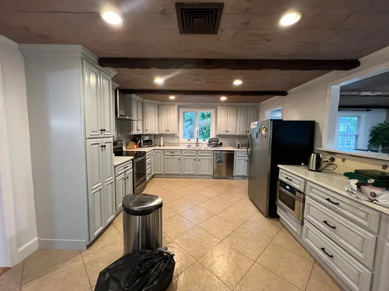 Painted kitchen with white cabinets and a wood ceiling