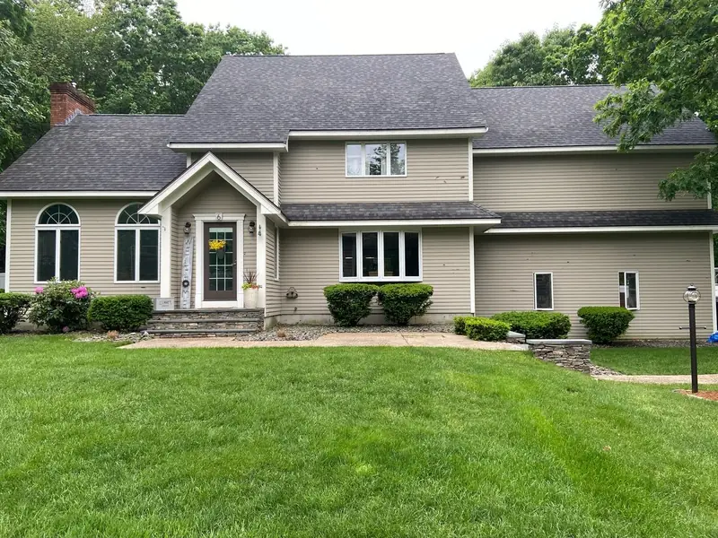 Tan two-story home with white trim and arched windows