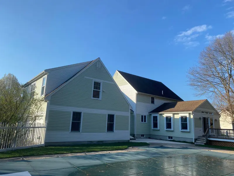 Cape home with light gray siding and a new deck