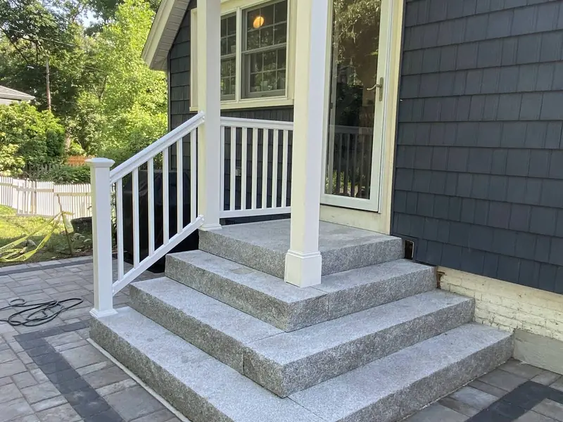 New porch steps with white railings on a dark gray home