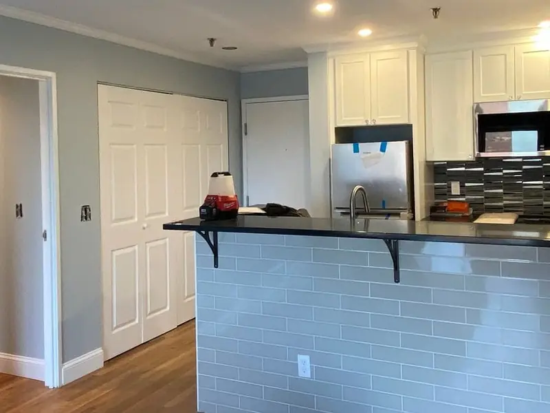 Painted kitchen with white cabinets and a gray tile backsplash