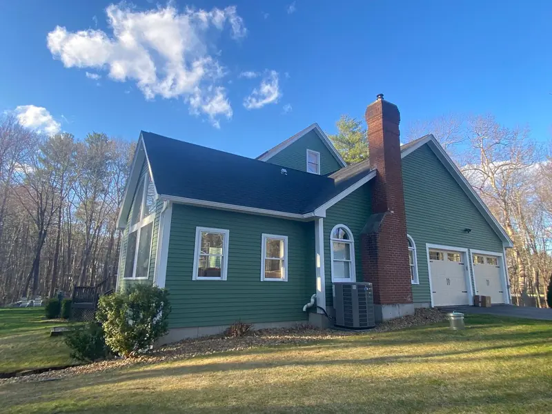Green home with white trim, chimney and new windows