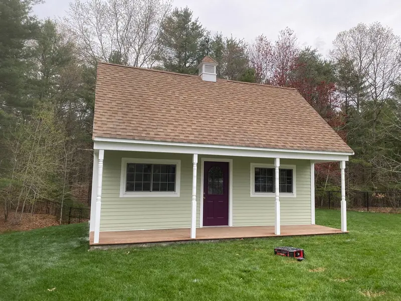 Cape style home with new light green siding and a covered porch
