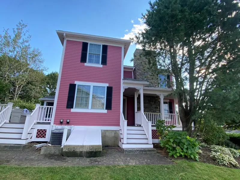 Pink two-story home with black shutters and a white porch